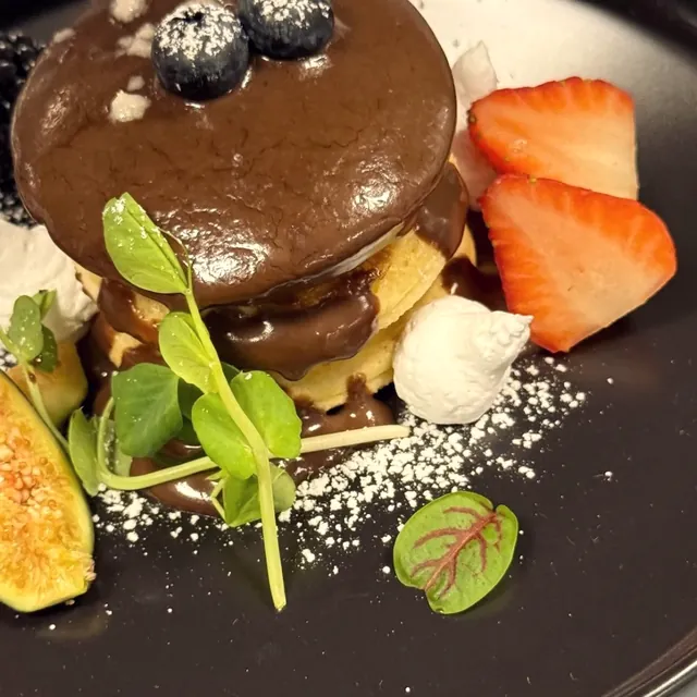 Postre de chocolate con fresas, higo y hojas pequeñas.