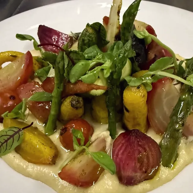 Verduras de temporada asadas: betabel, jitomate cherry y espárragos sobre un puré claro.